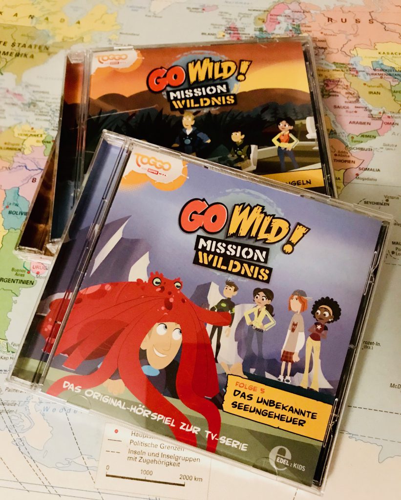 drei go wild cds liegen auf einer schreibtischunterlage, die eine Weltkarte zeigt